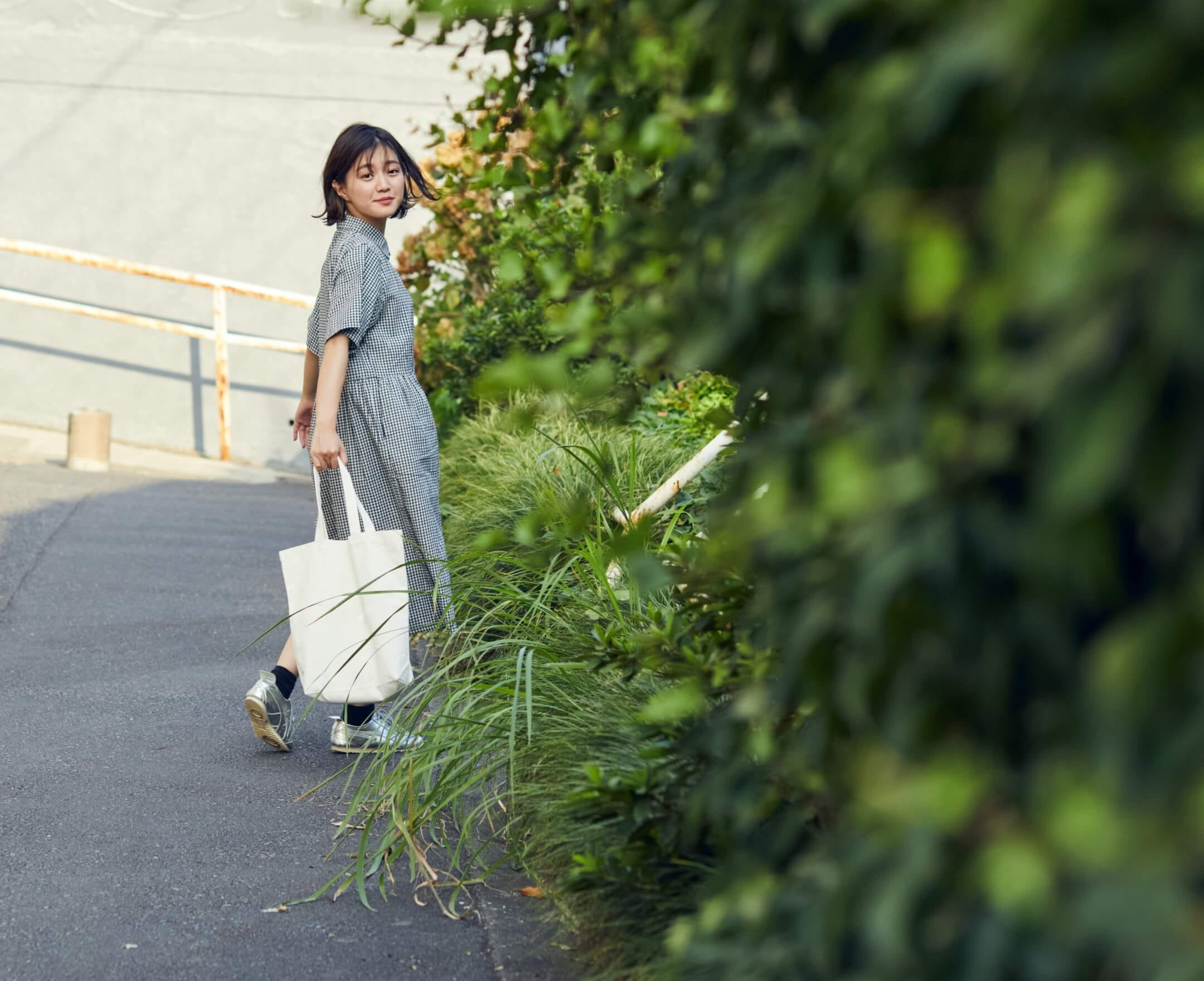 笑顔の素敵な道を歩くカジュアルな服装の女性